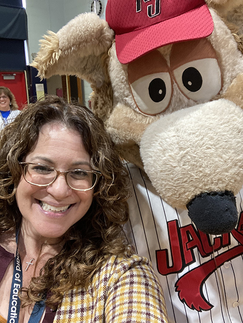 Teacher posing for a picture with school mascot