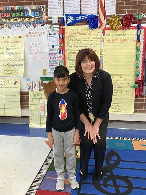 Siddh Shah posing for a picture with his teacher in the classroom