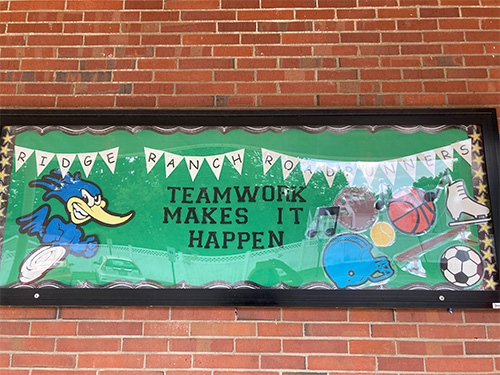 Teamwork Makes it Happen banner on a brick wall