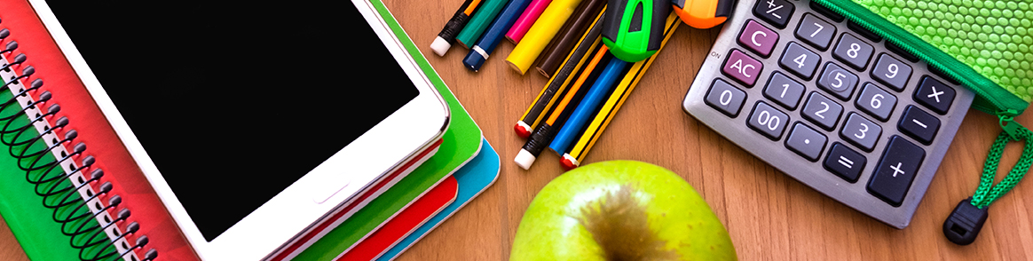 A desk with colorful books, calculator, and apple