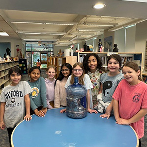 Smiling students around a jar with money in it