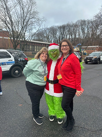 Two teachers in the parking lot with the Grinch