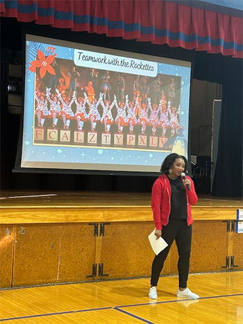 Member of the Rockettes during another part of her presentation with large presentation screen behind her