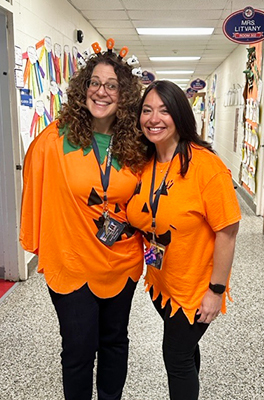 Two happy teachers dressed in pumpkin tops 