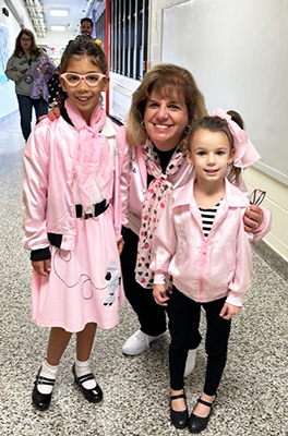Two students and an adults dressed in pink fifties attire for Halloween
